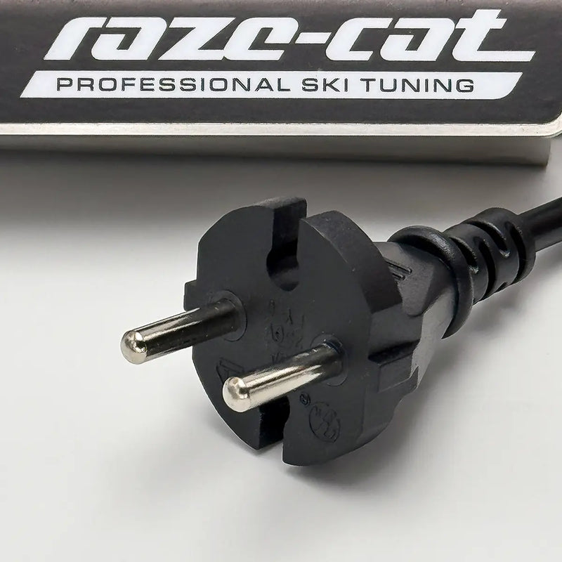 Laden Sie das Bild in Galerie -Viewer, Nahaufnahme eines schwarzen Euro-Steckers mit zwei Metallstiften und Kabel, vor einem Produkt mit der Aufschrift 'raze-cat PROFESSIONAL SKI TUNING'.
