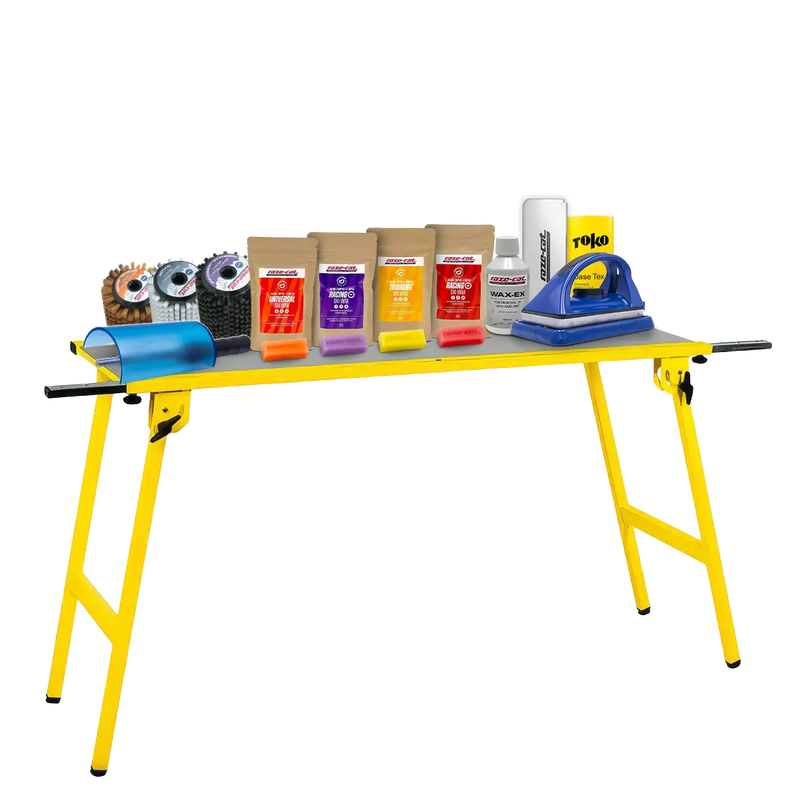 Cargue la imagen en el visor de galería, Gelber Klapptisch mit verschiedenen Wachsprodukten, Bürsten und einem Wachsbügeleisen für Ski- oder Snowboardpflege.
