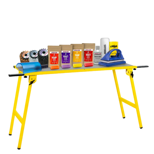 Gelber Klapptisch mit verschiedenen Wachsprodukten, Bürsten und einem Wachsbügeleisen für Ski- oder Snowboardpflege.